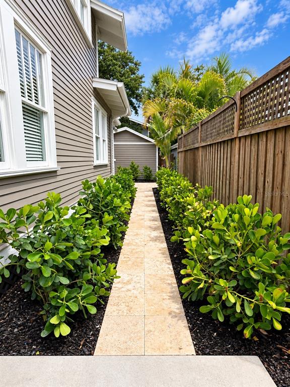 A stone walkway leads between a house with gray siding and a wooden privacy fence — 605 S ORLEANS AVENUE, TAMPA, FL