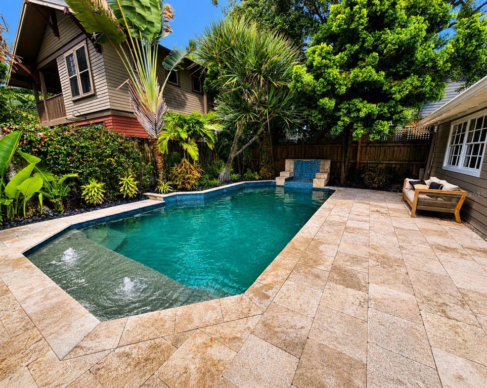 A backyard swimming pool with a stone patio, water features, and surrounding tropical landscaping — 605 S ORLEANS AVENUE, TAMPA, FL