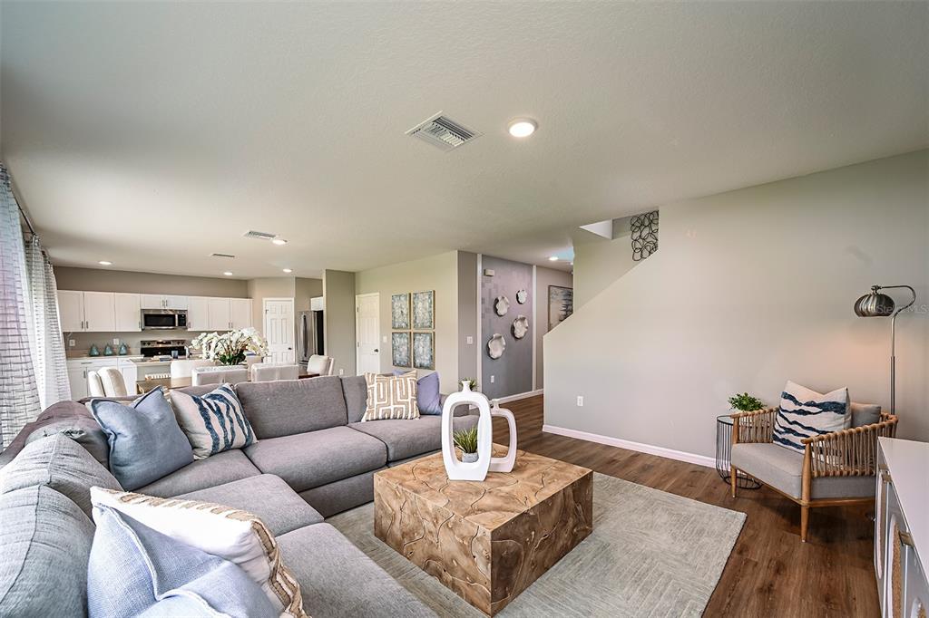 A living room features a gray sectional sofa, a wooden coffee table, and an armchair — 31731 OYSTER TRELLIS LANE, WESLEY CHAPEL, FL
