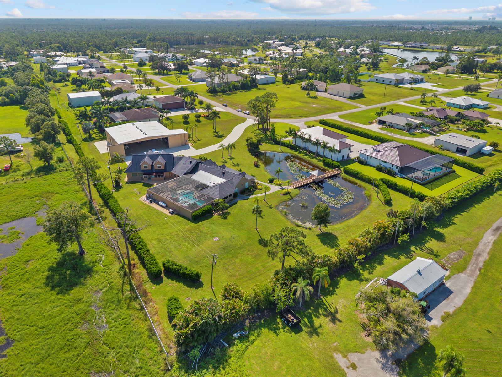 An aerial view shows a large residential property with a pool, pond, and outbuildings — 3561 Downwind Lane, FL 33917, FL