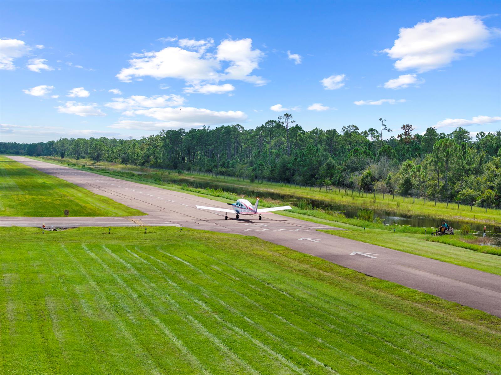A small airplane sits on an airport runway next to a grassy field and trees — 3561 Downwind Lane, FL 33917, FL