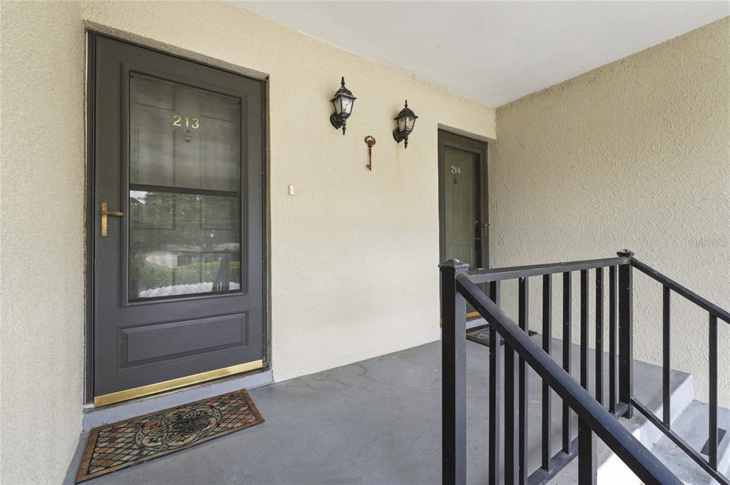 An exterior view shows two apartment doors labeled 213 and 214 with a metal railing — 689 LAKE HOWARD DRIVE NW UNIT 213, WINTER HAVEN, FL
