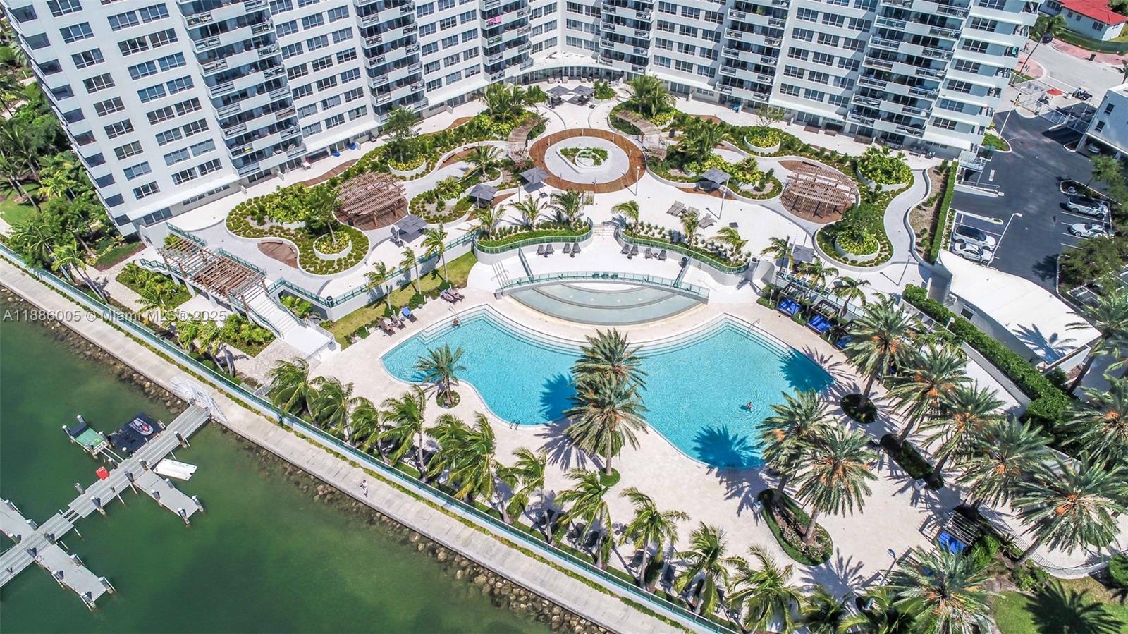 An aerial view shows a large swimming pool, landscaped courtyard, and boat dock by a building — 1500 Bay Rd # 122S, Miami Beach FL 33139, MIAMI BEACH, FL