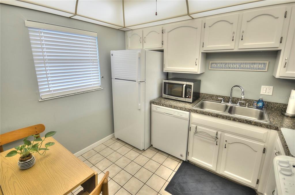 A kitchen with white cabinets, a white stove, and a pass-through window to the living area — 4155 S ATLANTIC AVENUE UNIT 403, NEW SMYRNA BEACH, FL
