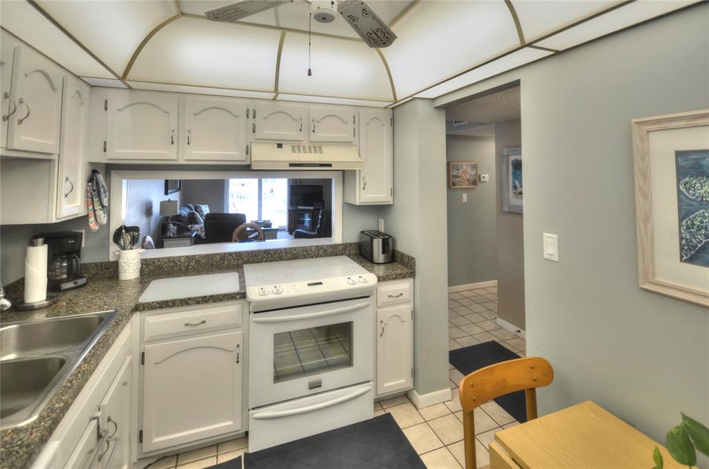A kitchen with a white electric cooktop, laminate countertops, and a small dining area — 4155 S ATLANTIC AVENUE UNIT 403, NEW SMYRNA BEACH, FL