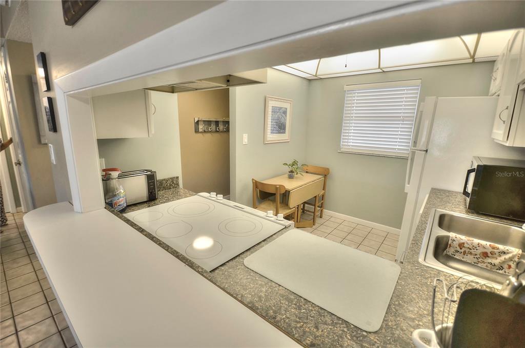 A dining area features a table with four chairs, tile flooring, and a kitchen pass-through — 4155 S ATLANTIC AVENUE UNIT 403, NEW SMYRNA BEACH, FL