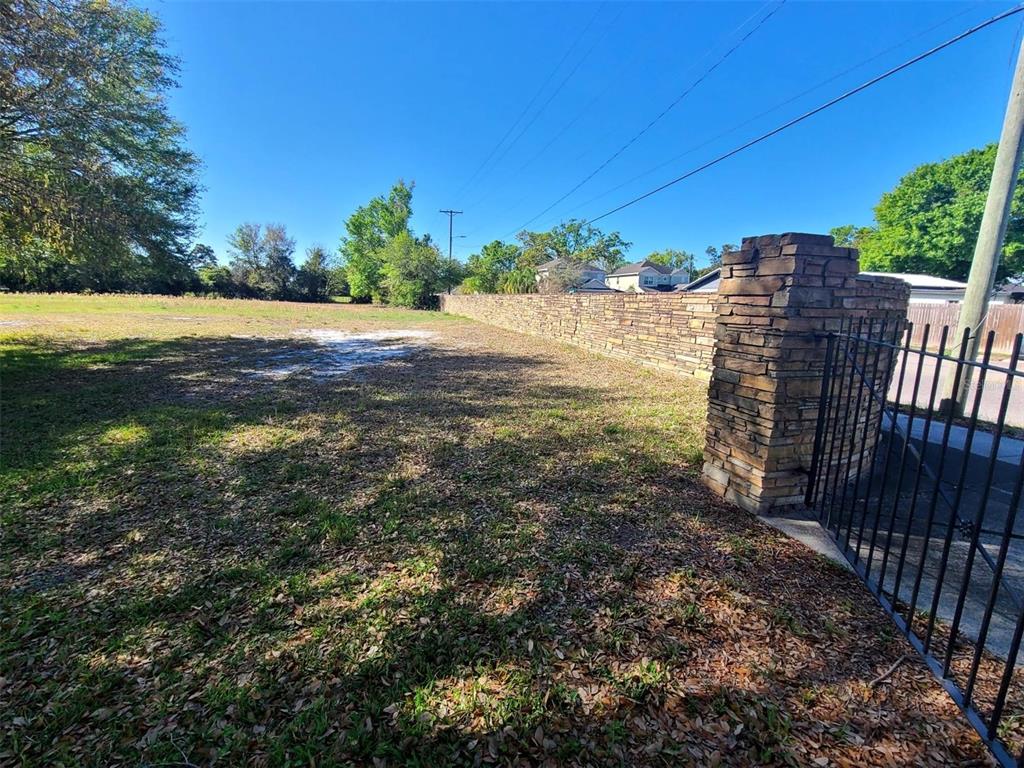 A vacant grassy lot features a stone wall and a metal gate entrance — 3541 N BOULEVARD, TAMPA, FL