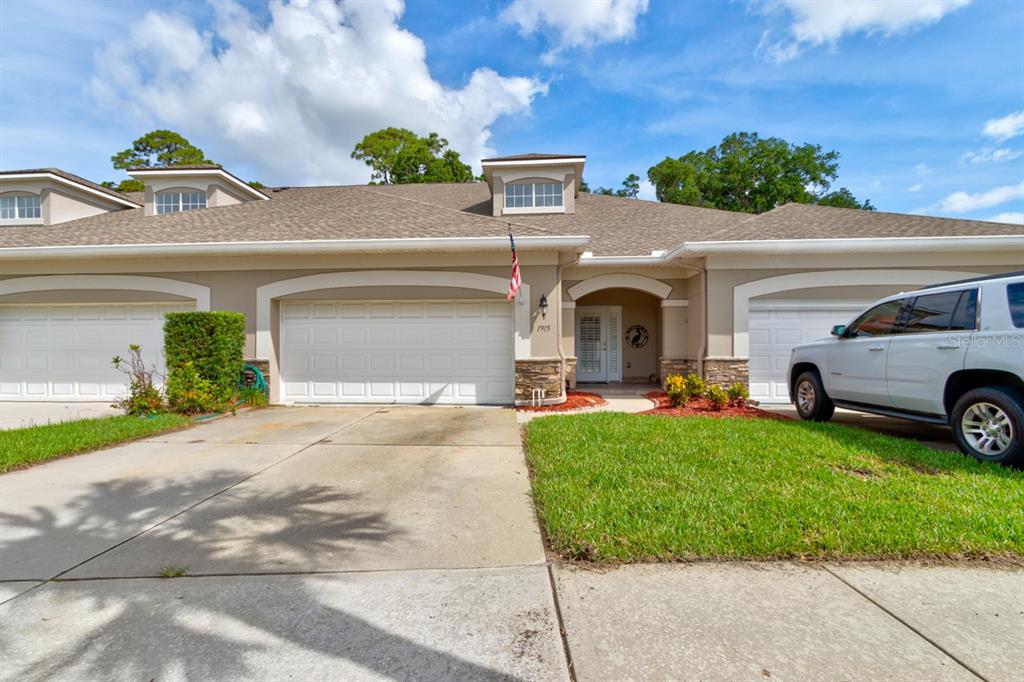 A tan, single-story townhouse with two garage doors and a white front door — 1915 TURNBULL LAKES DRIVE, NEW SMYRNA BEACH, FL