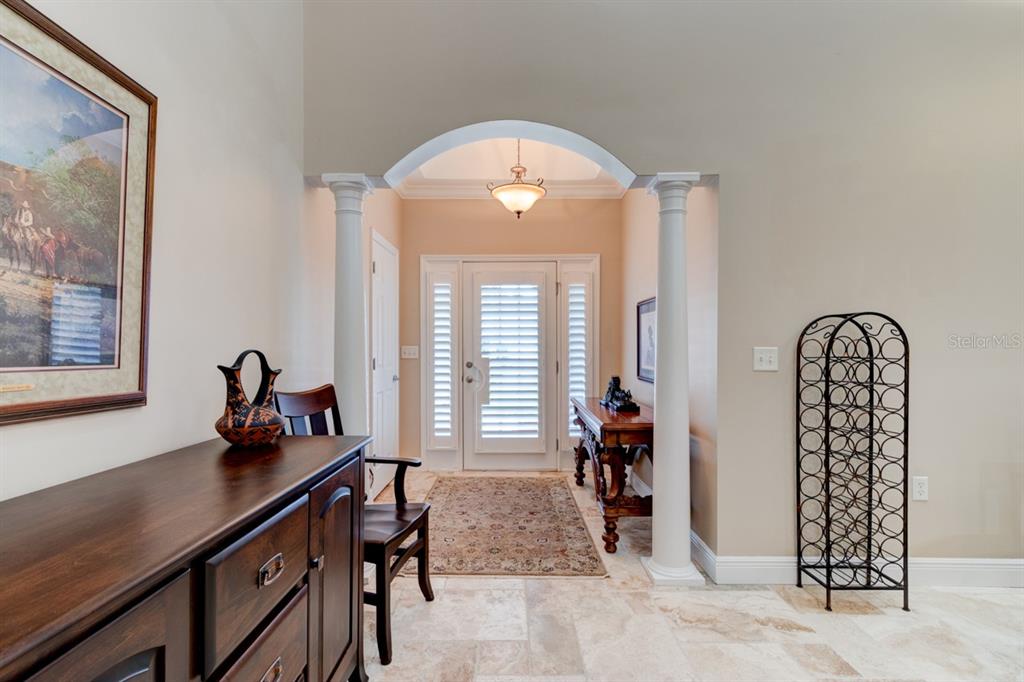 A foyer features an arched entryway with white columns, tile flooring, and a wooden console — 1915 TURNBULL LAKES DRIVE, NEW SMYRNA BEACH, FL