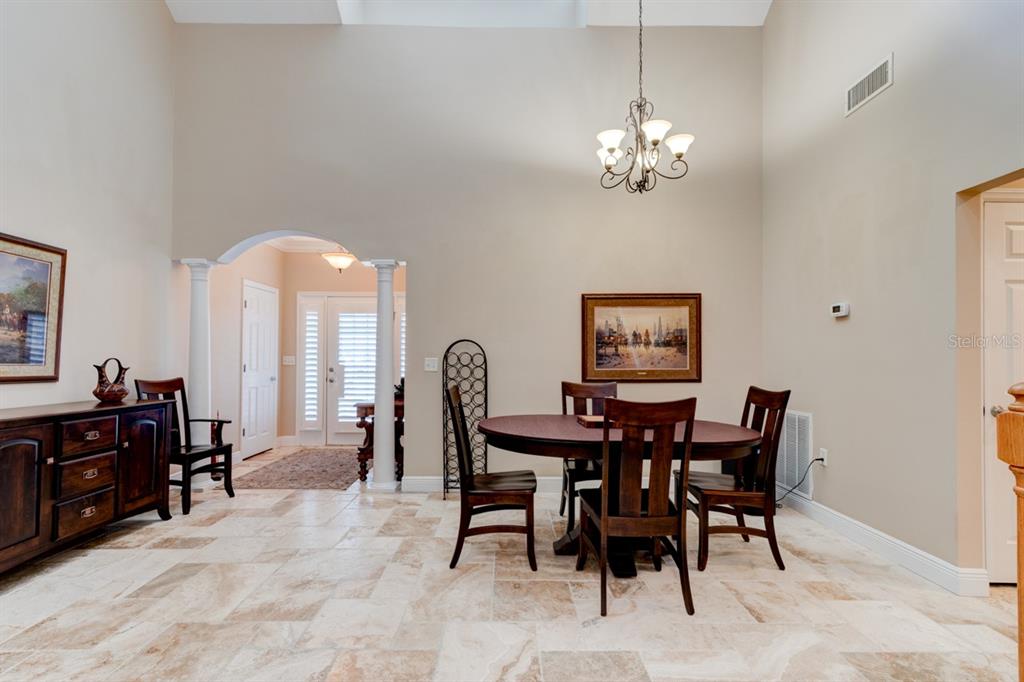A dining area features a round wooden table, chairs, tile flooring, and a vaulted ceiling — 1915 TURNBULL LAKES DRIVE, NEW SMYRNA BEACH, FL