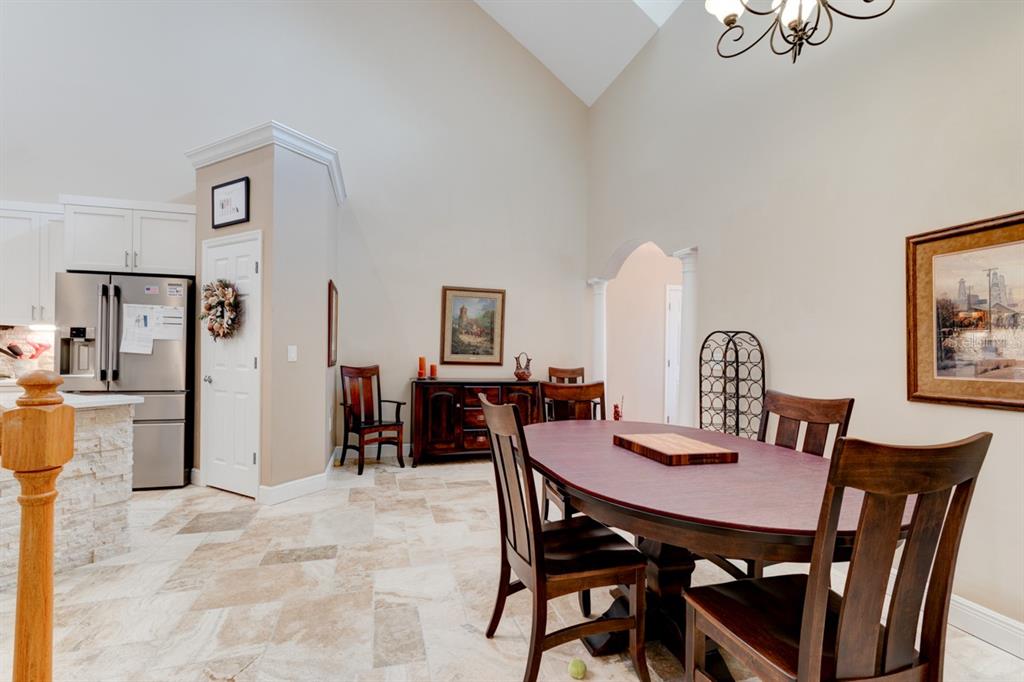 A dining area with a wooden table, chairs, tile flooring, and a high vaulted ceiling — 1915 TURNBULL LAKES DRIVE, NEW SMYRNA BEACH, FL