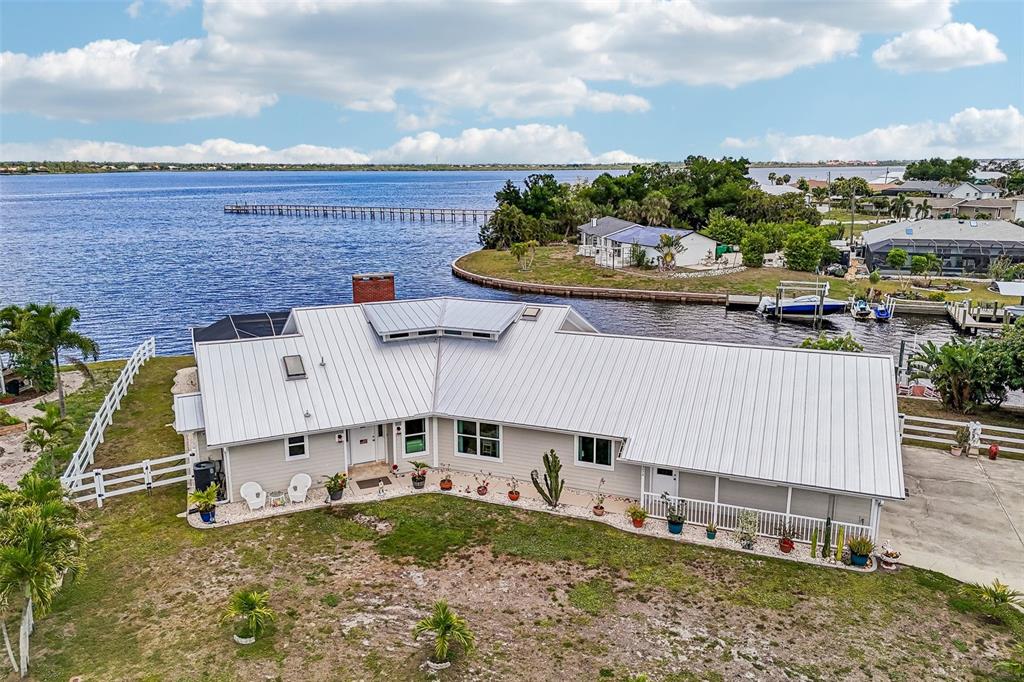 An aerial view of a waterfront house with a metal roof and a fenced yard — 3072 MAUCK TERRACE, PORT CHARLOTTE, FL