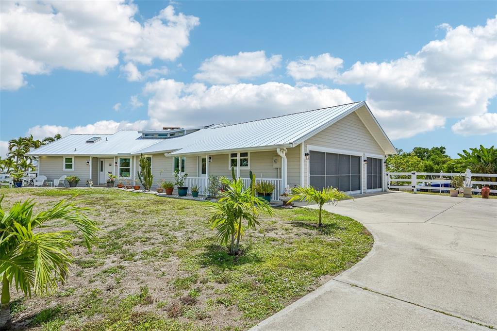 A single-story house with a metal roof, light siding, and a concrete driveway — 3072 MAUCK TERRACE, PORT CHARLOTTE, FL