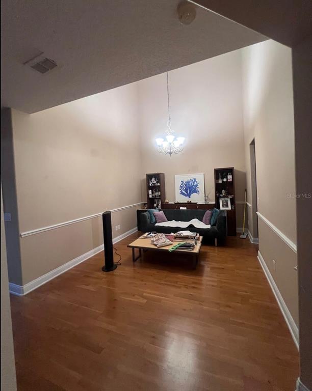 A living room with high ceilings, hardwood floors, a chandelier, and a dark sofa — 6845 PIAZZA STREET, ORLANDO, FL