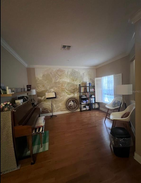 A room with hardwood floors, a floral accent wall, a piano, and two white chairs — 6845 PIAZZA STREET, ORLANDO, FL