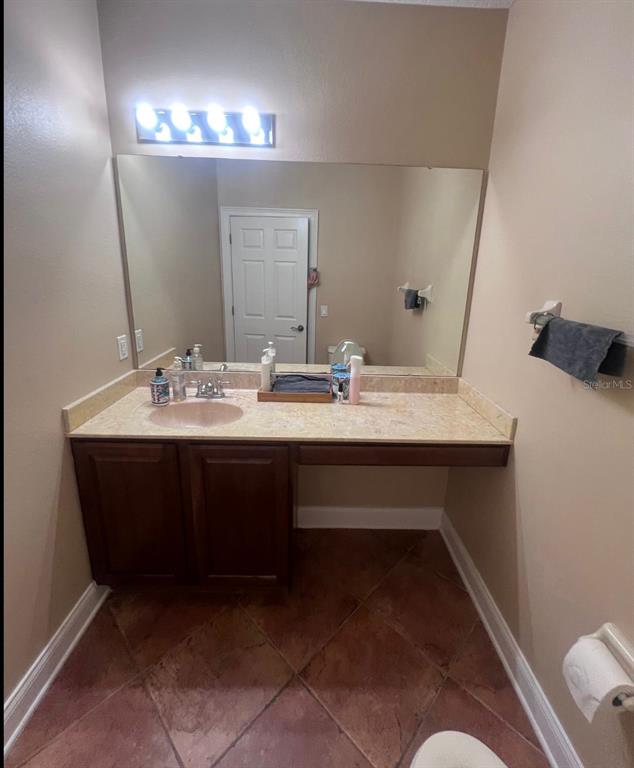 A bathroom features a vanity with a beige countertop, dark wood cabinets, and a large mirror — 6845 PIAZZA STREET, ORLANDO, FL