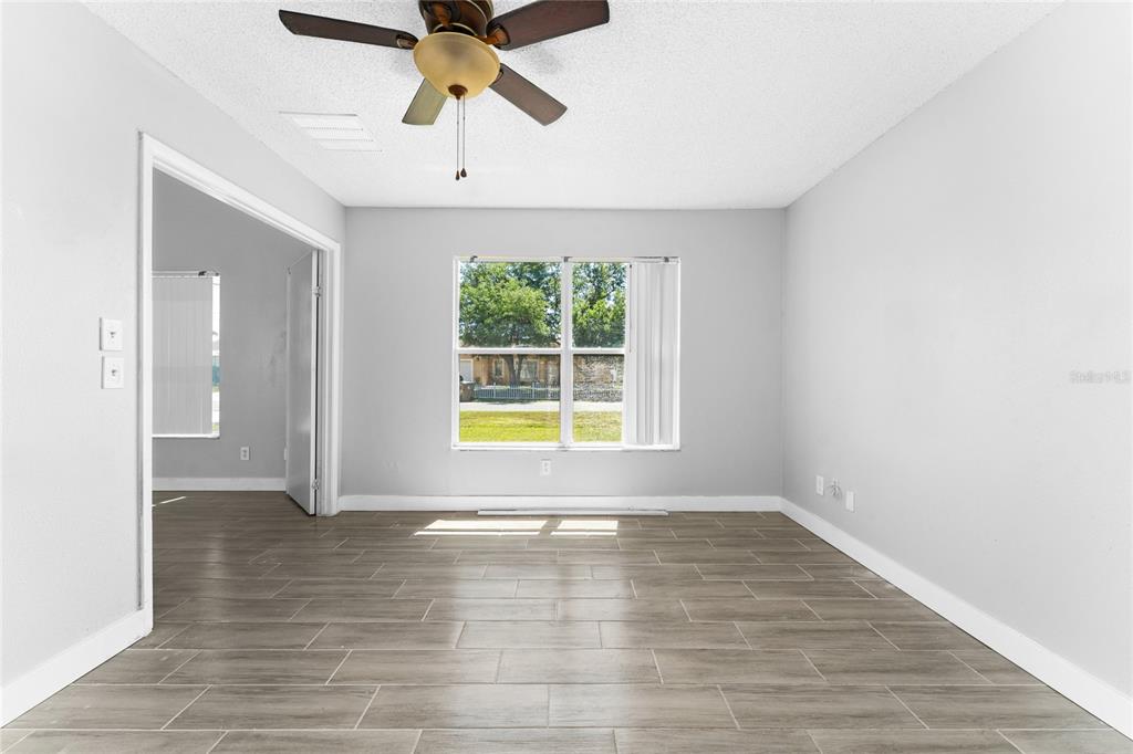 An empty room with gray walls, wood-look tile flooring, a ceiling fan, and a window — 309 CORNWALLIS COURT, KISSIMMEE, FL