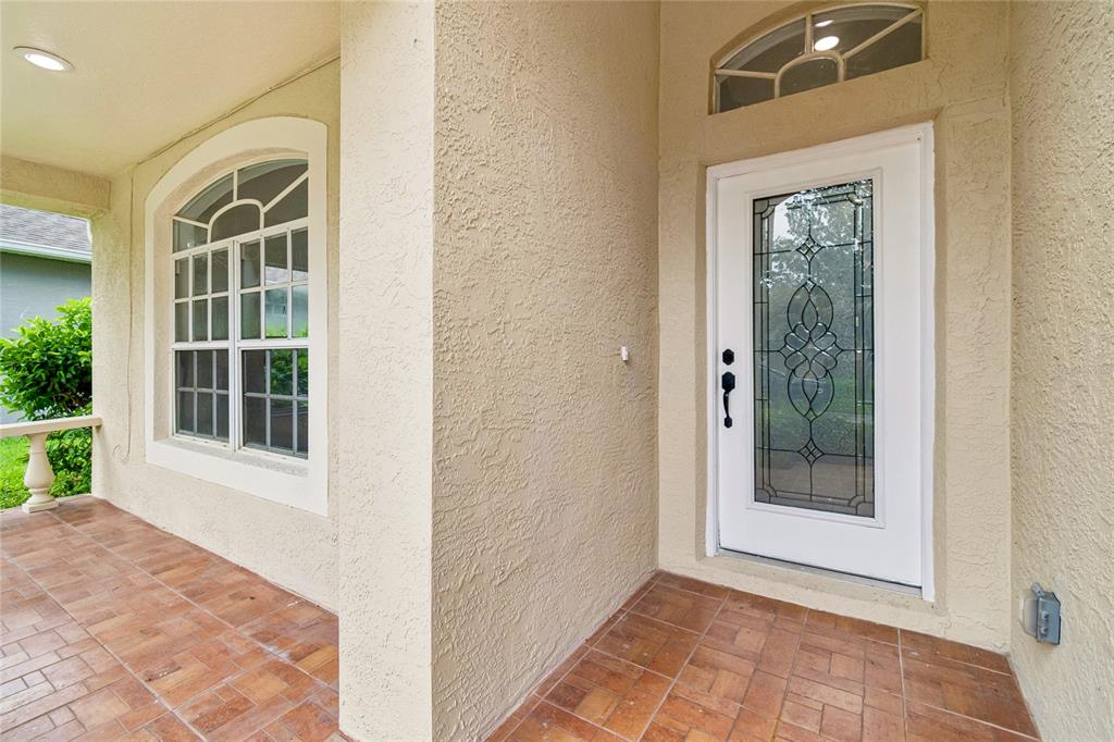 A covered entryway with a tiled floor, a white front door, and a large window — 3041 BEAVER POND TRAIL, VALRICO, FL