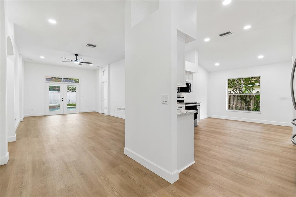 A bright, open-concept living and kitchen area features white walls and light wood flooring — 3041 BEAVER POND TRAIL, VALRICO, FL