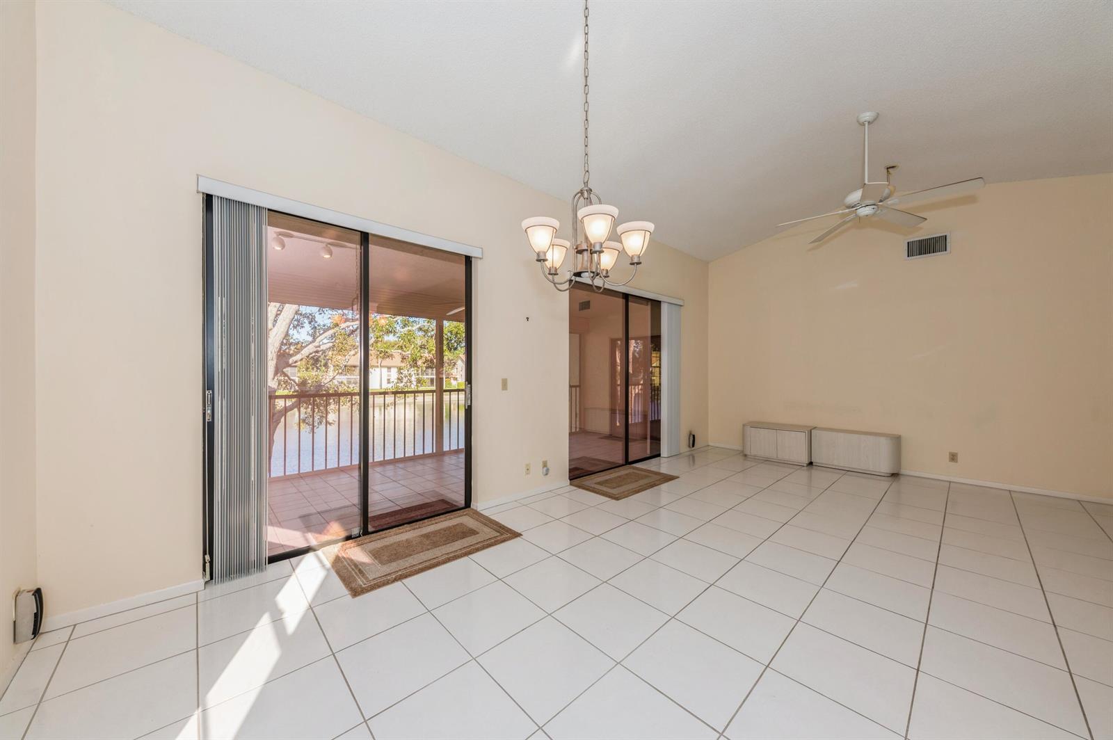 A bright dining area with white tile floors, a chandelier, and sliding doors to a balcony — 10439 S Circle Lake Drive # 201, Boynton Beach FL 33437, BOYNTON BEACH, FL