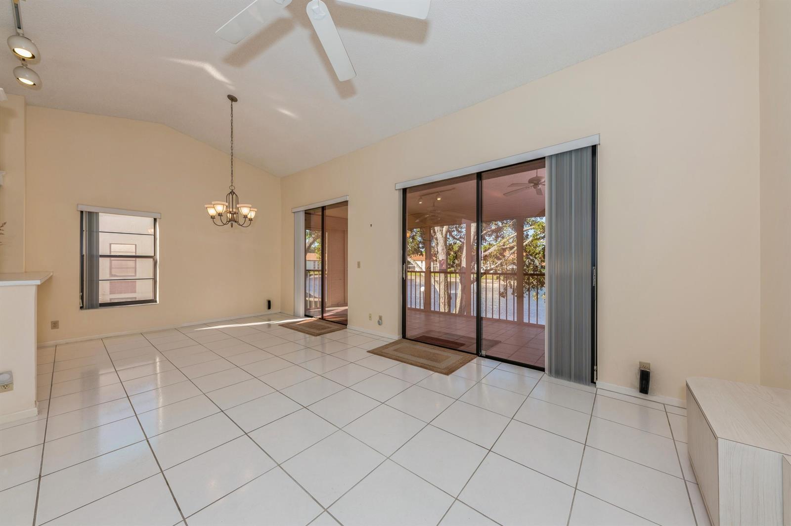 A bright room with white tile floors, a vaulted ceiling, and sliding glass doors — 10439 S Circle Lake Drive # 201, Boynton Beach FL 33437, BOYNTON BEACH, FL