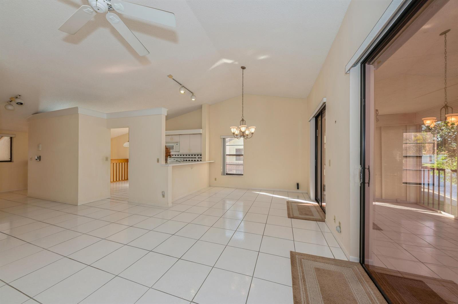 A bright dining area with white tile floors, a chandelier, and sliding glass patio doors — 10439 S Circle Lake Drive # 201, Boynton Beach FL 33437, BOYNTON BEACH, FL