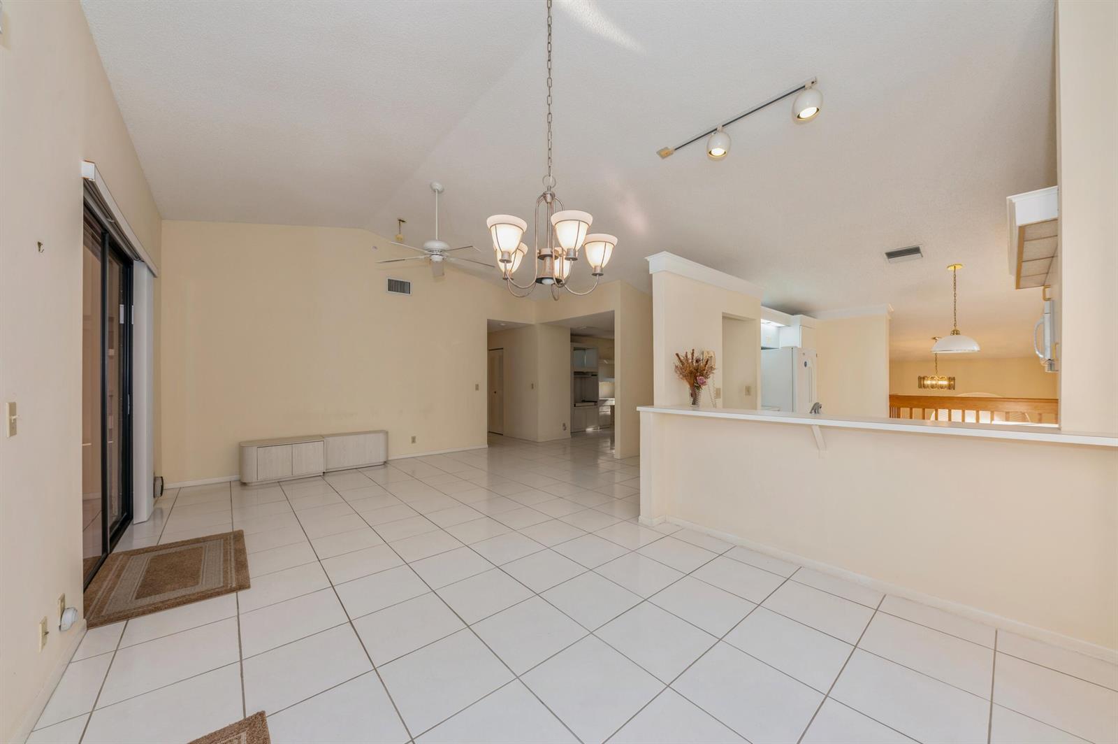 A bright, open-concept living and dining area features white tile floors and a vaulted ceiling — 10439 S Circle Lake Drive # 201, Boynton Beach FL 33437, BOYNTON BEACH, FL
