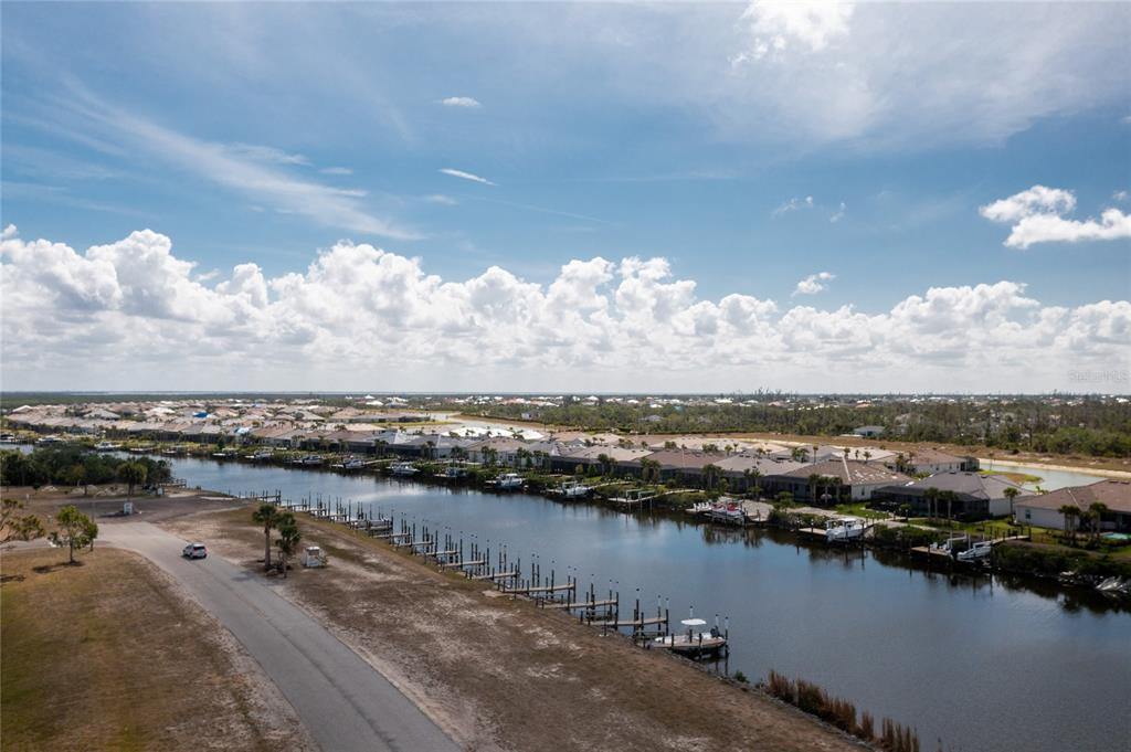 An aerial view shows a canal lined with boat docks and residential houses under clouds — 7412 HESTON STREET, PORT CHARLOTTE, FL