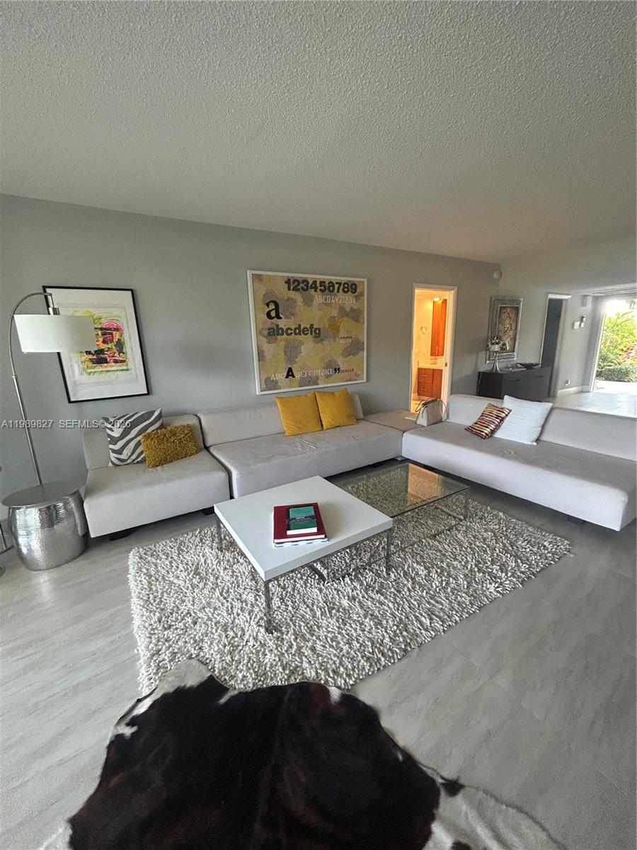 A living room features a large sectional sofa, a white coffee table, and abstract wall art — 4017 N Cypress Dr # 102, Pompano Beach FL 33069, POMPANO BEACH, FL