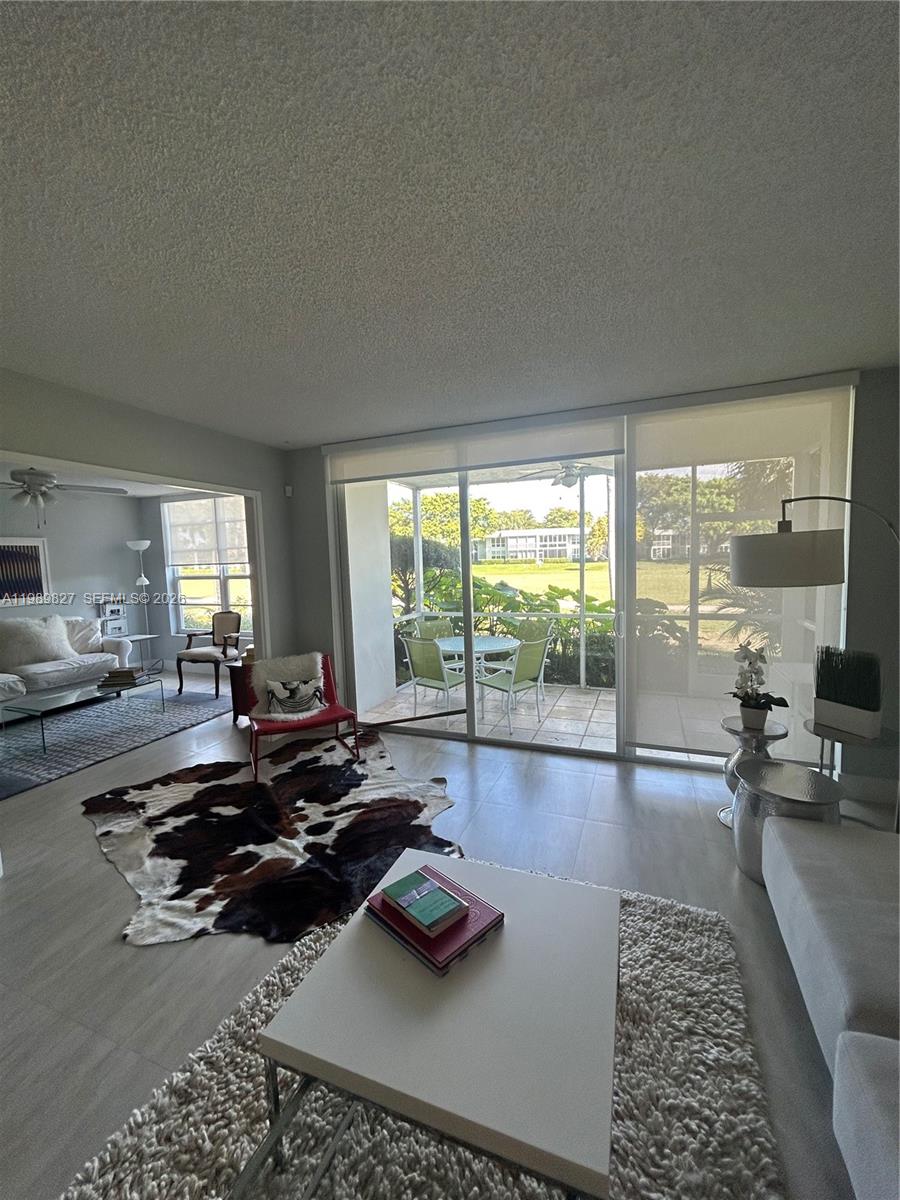 A bright living room features a cowhide rug, sliding glass doors, and a screened patio — 4017 N Cypress Dr # 102, Pompano Beach FL 33069, POMPANO BEACH, FL