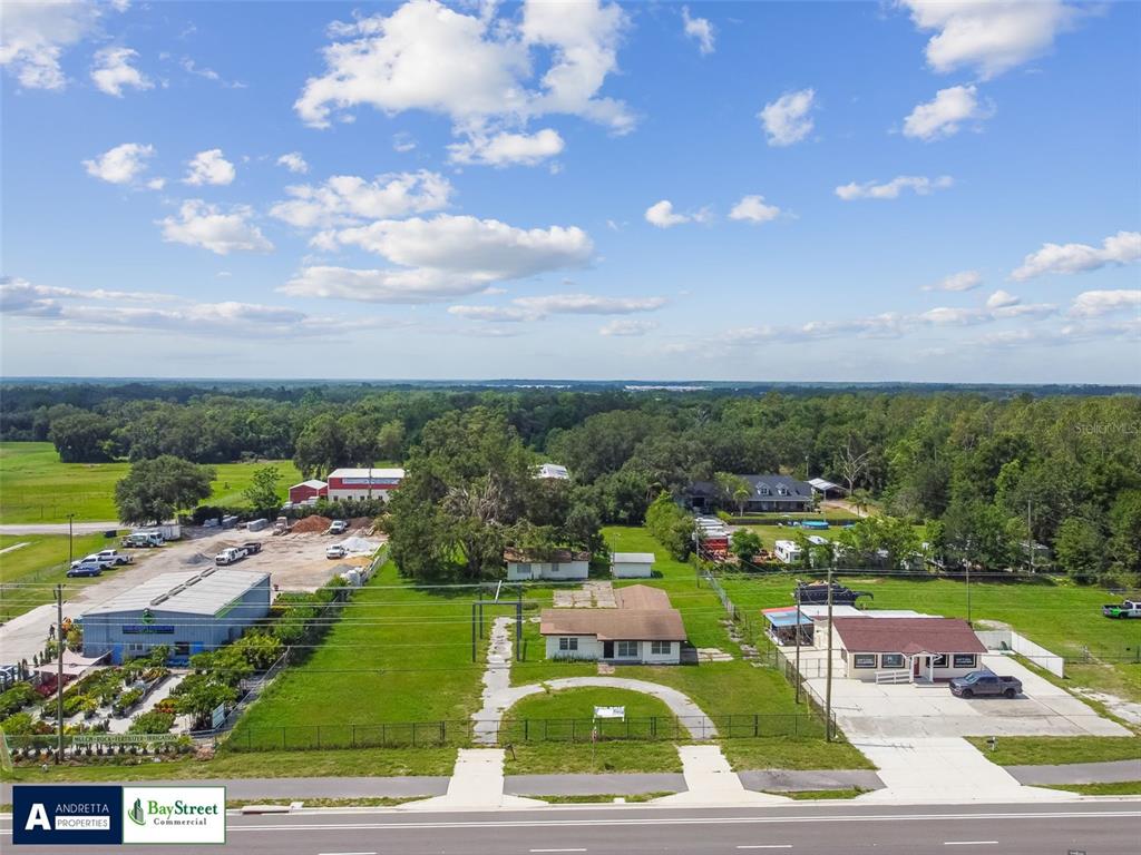 An aerial view shows a commercial property with a house and several outbuildings near a road — 34020 & 34024 STATE ROAD 54, WESLEY CHAPEL, FL