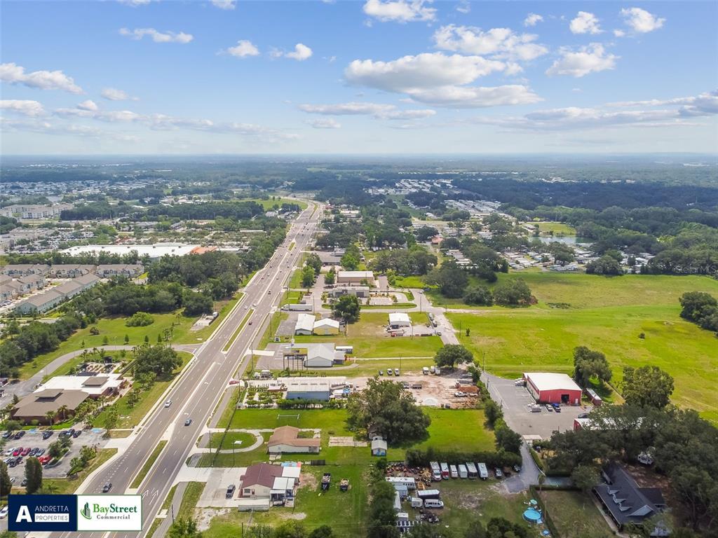 An aerial view shows a multi-lane highway running through a landscape of commercial and residential properties — 34020 & 34024 STATE ROAD 54, WESLEY CHAPEL, FL