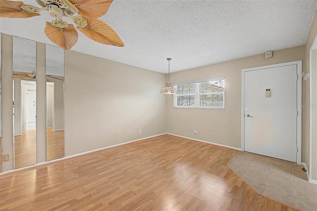 An empty dining room with wood-look flooring, a ceiling fan, and a mirrored wall — 11485 OAKHURST ROAD UNIT 204, LARGO, FL