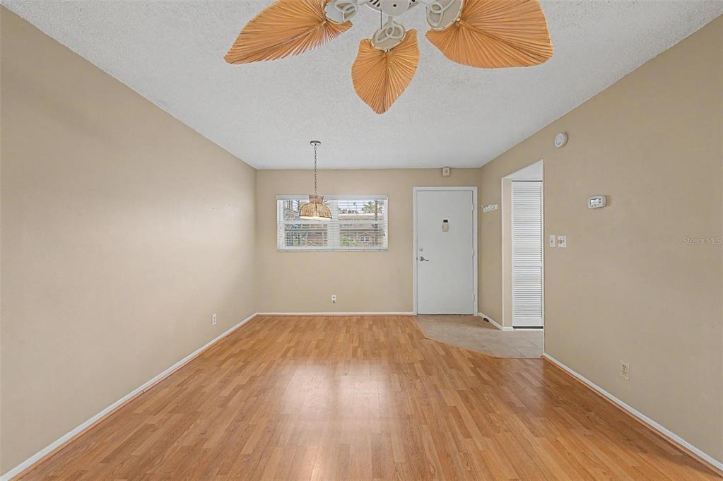 An empty room with wood-look flooring, a ceiling fan, and a white entry door — 11485 OAKHURST ROAD UNIT 204, LARGO, FL
