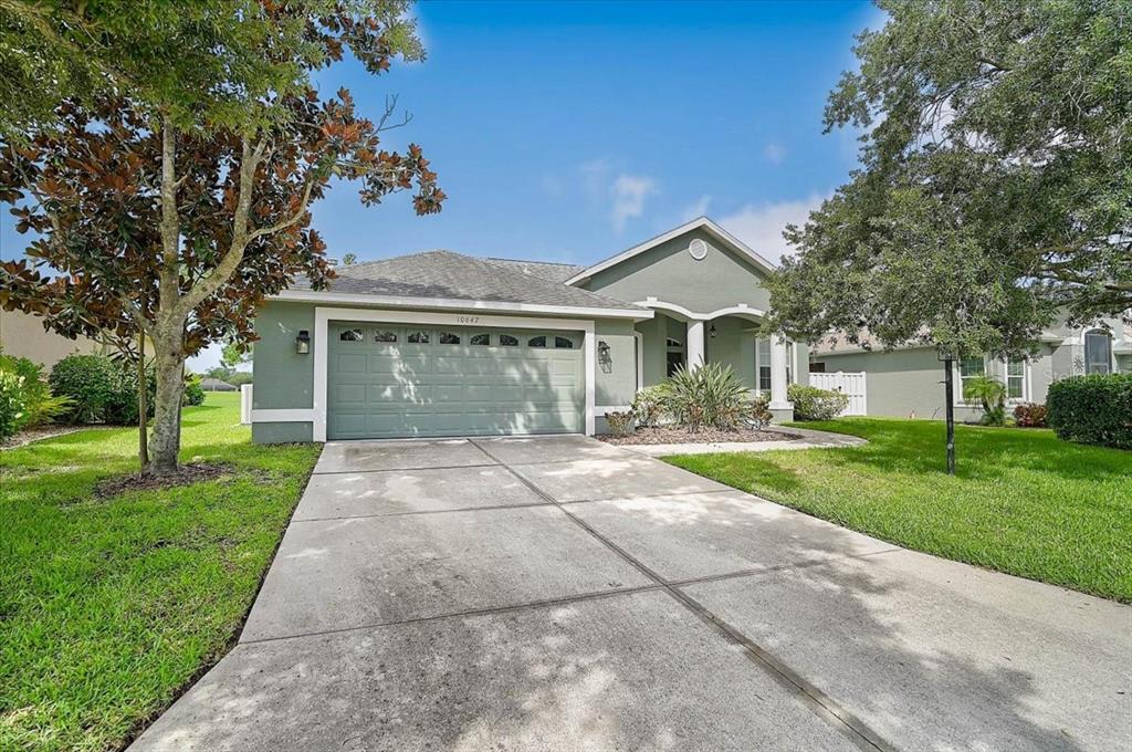 A single-story house with a green exterior, a two-car garage, and a concrete driveway — 10647 OLD GROVE CIRCLE, BRADENTON, FL