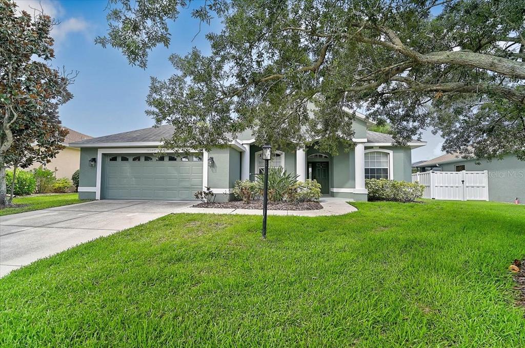 A single-story house with a green exterior, two-car garage, and a large front lawn — 10647 OLD GROVE CIRCLE, BRADENTON, FL