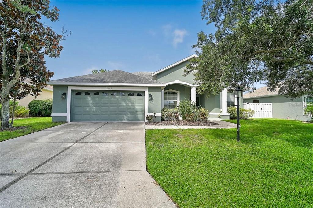 A single-story house with a green exterior, a two-car garage, and a front lawn — 10647 OLD GROVE CIRCLE, BRADENTON, FL