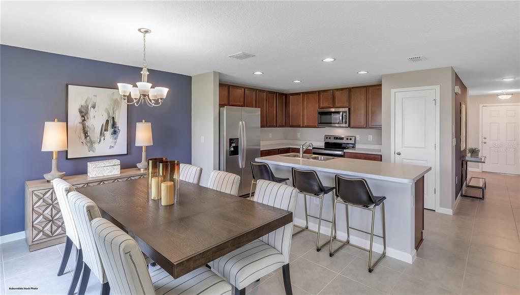A dining area with a wooden table and chairs sits adjacent to a kitchen island — 4121 PENELOPE AVENUE, LAKE WALES, FL