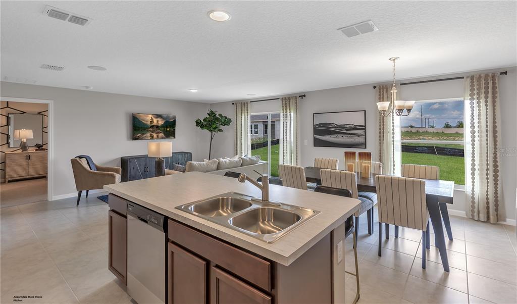 A kitchen island with a double sink overlooks an open-concept dining and living area — 4121 PENELOPE AVENUE, LAKE WALES, FL