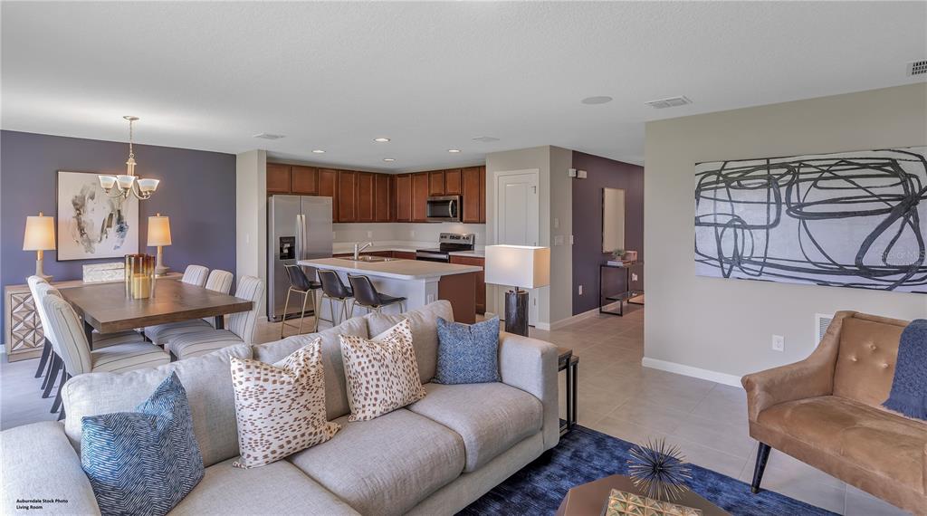 An open-concept living room and kitchen feature a dining area, island seating, and neutral decor — 4121 PENELOPE AVENUE, LAKE WALES, FL