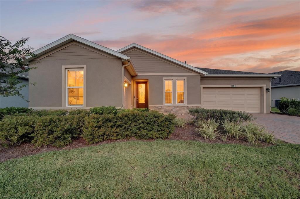 A single-story suburban house with a tan stucco exterior, stone accents, and a two-car garage — 4436 NW 53RD COURT, OCALA, FL