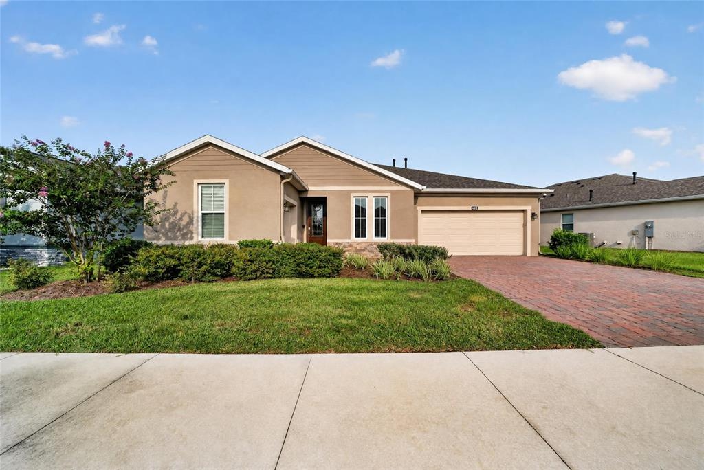 A single-story suburban house with a tan stucco exterior, a brick driveway, and a garage — 4436 NW 53RD COURT, OCALA, FL
