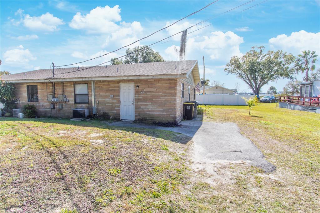 A single-story brick building with a white door and a small asphalt driveway — 709 MOSLEY ROAD, LAKE ALFRED, FL