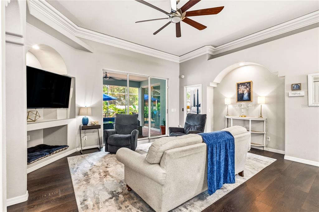 A living room features a beige sofa, two recliners, a television niche, and dark wood floors — 1015 ROBIN LANE, WINTER HAVEN, FL