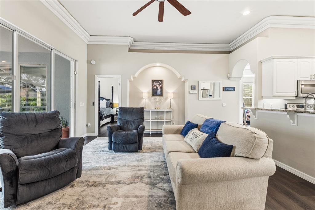 A living room features a beige sofa, two recliners, an arched alcove, and kitchen access — 1015 ROBIN LANE, WINTER HAVEN, FL