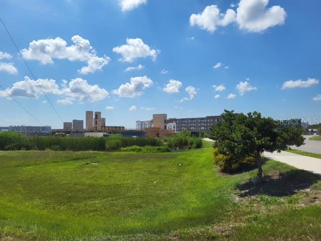A grassy field sits in the foreground with modern apartment buildings visible in the distance — S APOPKA VINELAND, ORLANDO, FL