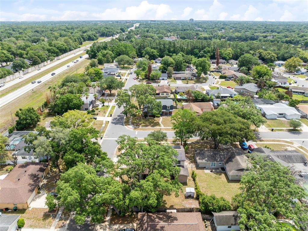 An aerial view shows a suburban neighborhood with houses, mature trees, and a nearby highway — 8698 HILLSIDE DRIVE, ORLANDO, FL