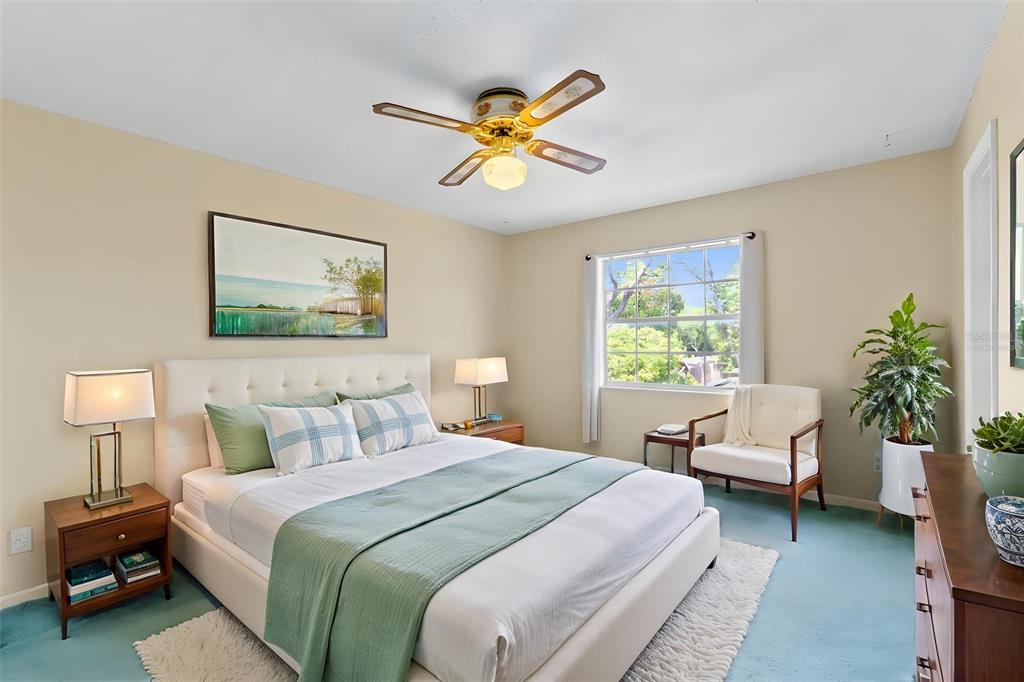 A bedroom features a bed with a light green throw, a ceiling fan, and a window — 8698 HILLSIDE DRIVE, ORLANDO, FL