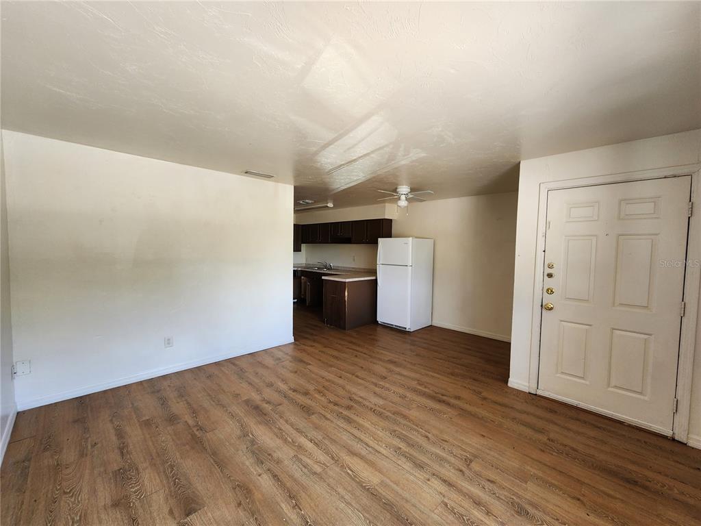 An interior view shows a living area with wood-look flooring leading to a kitchen — 719 SW 70TH TERRACE UNIT 5, GAINESVILLE, FL