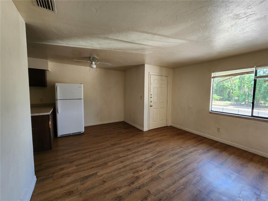 An interior view of a room with wood-look flooring, a white refrigerator, and a window — 719 SW 70TH TERRACE UNIT 5, GAINESVILLE, FL